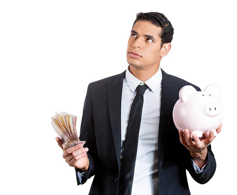 man holding piggy bank in one hand and money in the other looking confused
